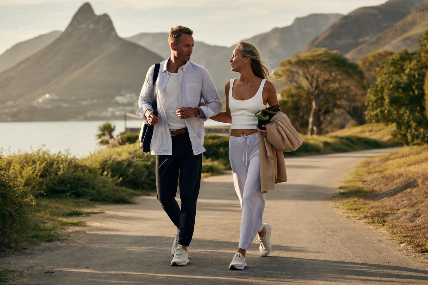 A healthy mature couple walking together along a Cape Town coastal path with the mountains behind them